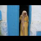 Una mujer ante la puerta de su casa en Asilah.